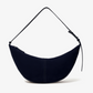 The Proenza Schouler Slide Suede Bag features a crescent shape, soft suede construction, single adjustable strap, and curved silhouette, shown against a plain white background.