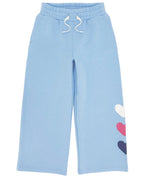 Feather 4 Arrow Girls’ Heart Sweatpant in light blue features a relaxed fit, white drawstrings, and three heart-shaped patches in white, pink, and navy on the lower left leg.