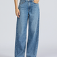 A person wears Rag & Bone's Featherweight Logan Wide jeans in light blue with a black sleeveless top and black sandals, standing against a plain light background.