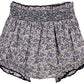 The Kidiwi Baby Girls' Myrtille Smocked Bloomer features a navy blue floral print, 100% cotton fabric, an elastic waistband, and delicate smocking at the top.