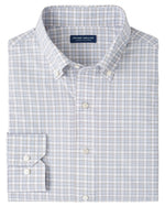 The Peter Millar Carter Performance Poplin Sport Shirt is a neatly folded men’s long-sleeve button-down in a blue, gray, and white plaid pattern with a Peter Millar label on the inside collar.