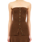 A person wearing the Ulla Johnson Yanni Strapless Knit Top, a brown ribbed knit tube top featuring front button detailing. The upper part of the skirt is also visible against a white background.