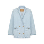 The Nariida Cory Jacket by Blaze Milano is a light blue denim, oversized double-breasted blazer with notched lapels, two front pockets, and metal buttons, shown on a plain white background.