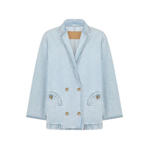 The Nariida Cory Jacket by Blaze Milano is a light blue denim, oversized double-breasted blazer with notched lapels, two front pockets, and metal buttons, shown on a plain white background.