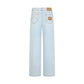 The Nariida Potoroo Jeans by Blaze Milano are light ice-blue wide leg jeans shown from the back, featuring two rear pockets, tan stitching, and a brown patch with a design on the right pocket.