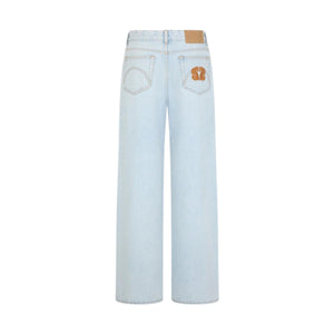 The Nariida Potoroo Jeans by Blaze Milano are light ice-blue wide leg jeans shown from the back, featuring two rear pockets, tan stitching, and a brown patch with a design on the right pocket.