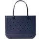 The Original Bogg® Bag by Bogg Bags is a navy blue tote featuring perforated holes, two sturdy handles, and a rubber-like construction. This stylish, washable beach bag has “Bogg” embossed on the lower right corner.