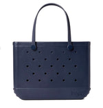 The Original Bogg® Bag by Bogg Bags is a navy blue tote featuring perforated holes, two sturdy handles, and a rubber-like construction. This stylish, washable beach bag has “Bogg” embossed on the lower right corner.