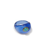 The Monument Ring by Lizzie Fortunato is a blue translucent hand-blown glass cocktail ring with a small green oval stone in a gold-colored bezel, shown on a plain white background.