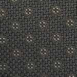 Close-up of the Robert Jensen Clover Pattern Tie, handcrafted by California Central Coast artisans, featuring a geometric motif of brown and white four-petaled flowers on a dark background.