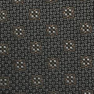 Close-up of the Robert Jensen Clover Pattern Tie, handcrafted by California Central Coast artisans, featuring a geometric motif of brown and white four-petaled flowers on a dark background.
