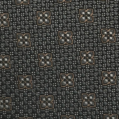 Close-up of the Robert Jensen Clover Pattern Tie, handcrafted by California Central Coast artisans, featuring a geometric motif of brown and white four-petaled flowers on a dark background.