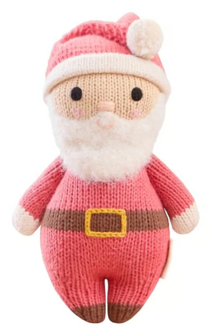 Introducing Baby Santa by Cuddle + Kind—a delightfully soft knitted doll featuring a red hat, white beard, rosy cheeks, and a yellow-buckled belt, shown against a white background. The perfect holiday companion for cozy baby snuggles.
