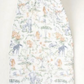 Timo & Violet Shawl Blanket made from soft organic cotton muslin, showcasing a gentle safari animal and plant pattern in muted tones, rolled at the top and displayed flat against a plain background.