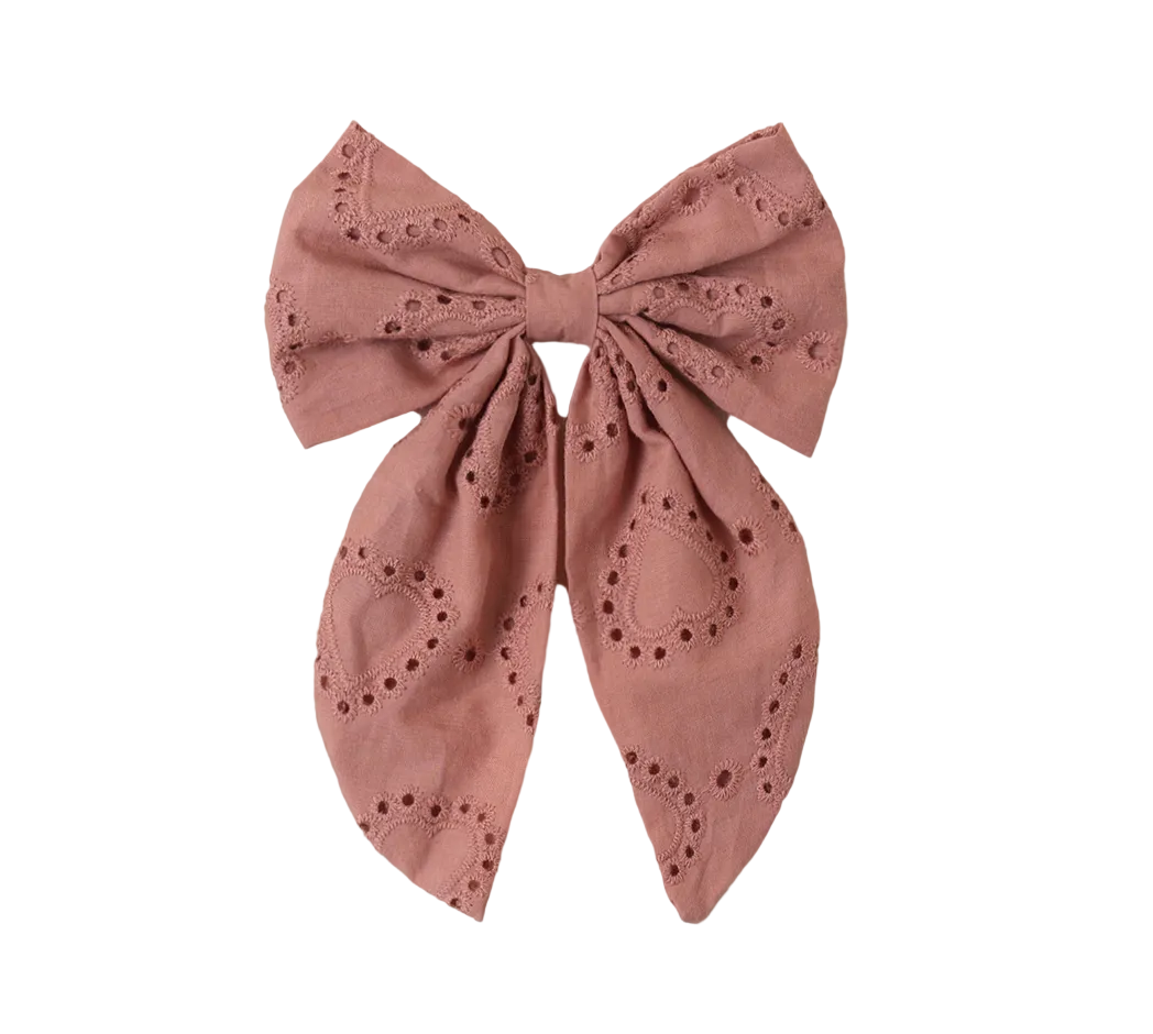 The Girls' Everly Bow by Noralee features pink fabric with embroidered heart cutouts and scalloped edges—an adorable accessory for girls, shown on a white background.