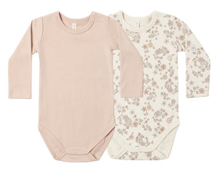 The Quincy Mae Baby Jersey Bodysuit 2-Pack features two long-sleeve one-piece bodysuits—one in solid light pink and the other in cream adorned with a pink and brown floral pattern. Made from soft brushed jersey with convenient snap closures at the bottom, these organic baby onesies offer everyday comfort.