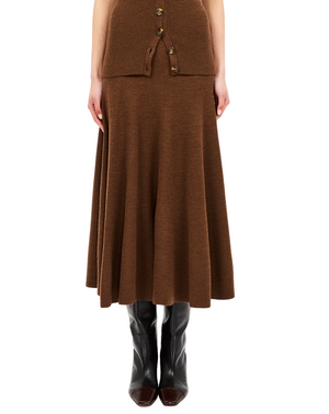 A person wearing the Ulla Johnson Azaria Knit Skirt in brown merino wool, styled with a coordinating buttoned top and black knee-high boots, shown from shoulders down.