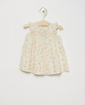 Bonpoint Baby Girls' and Girls' Narni Blouse with Cherry Print, sleeveless with ruffle sleeves, crafted from white organic cotton, shown on a wooden hanger against a plain white background.