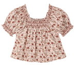 Girls’ Ada Blouse by Rylee & Cru features short ruffle sleeves, a light pink fabric with a red floral pattern, and a smocked square neckline and sleeve cuffs.