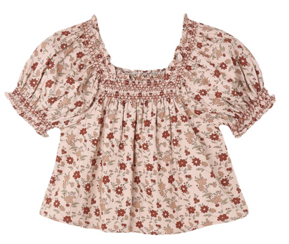Girls’ Ada Blouse by Rylee & Cru features short ruffle sleeves, a light pink fabric with a red floral pattern, and a smocked square neckline and sleeve cuffs.