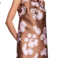 A person wears the Dorothee Schumacher Floral Statement Dress, a sleeveless brown duchesse twill shift featuring pink and white floral patterns and a neckline bow.