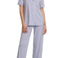 A woman stands barefoot wearing the Eberjey Gisele Short Sleeve Long Pant PJ Set—a light blue, classic fit pajama with short sleeves and matching straight leg pants featuring an elastic waistband.