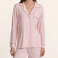 A woman wears the Eberjey Gisele Long PJ Set: a light pink, long-sleeve button-front top with collar and chest pocket, paired with matching straight-leg pants.