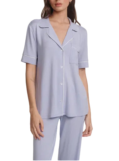 A woman wears the Eberjey Gisele Short Sleeve Long Pant PJ Set—light purple, classic fit with white piping, matching straight-leg pants, and an elastic waistband.