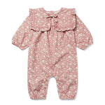 Discover the Baby Girls’ Celiciane Romper by Louis Louise—a charming pink floral print jumpsuit featuring long sleeves, a ruffled collar, and convenient button closures at the legs. Crafted from soft cotton twill, it showcases a delicate white flower pattern throughout.