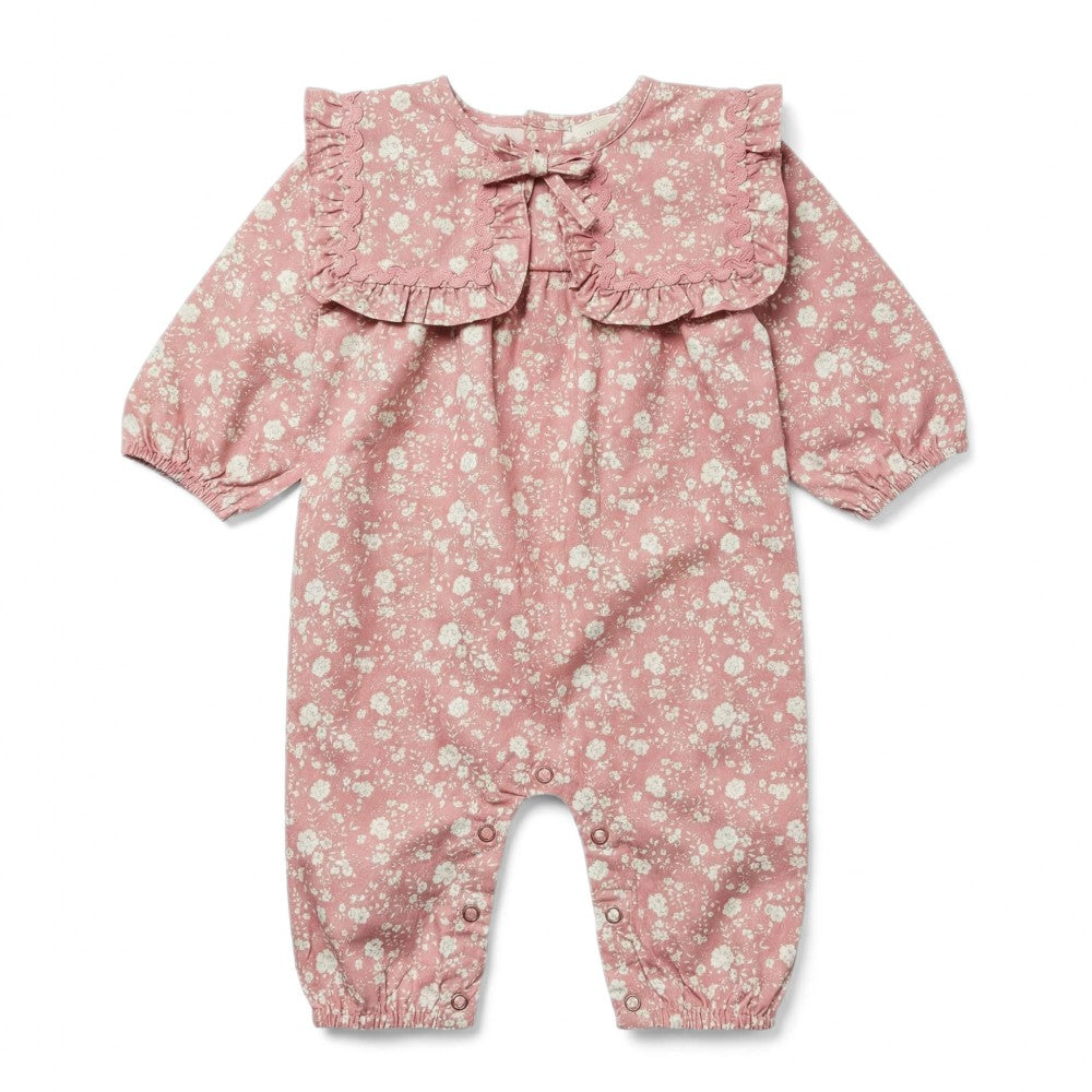 Discover the Baby Girls’ Celiciane Romper by Louis Louise—a charming pink floral print jumpsuit featuring long sleeves, a ruffled collar, and convenient button closures at the legs. Crafted from soft cotton twill, it showcases a delicate white flower pattern throughout.