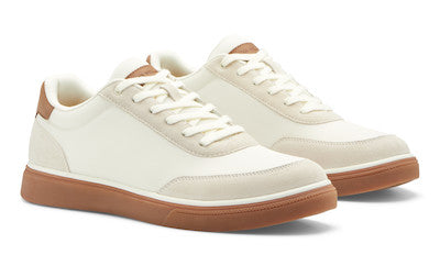 The Peter Millar Drift Mesh Sneaker features off-white performance mesh uppers, white laces, and brown rubber soles with herringbone traction, displayed on a white background.