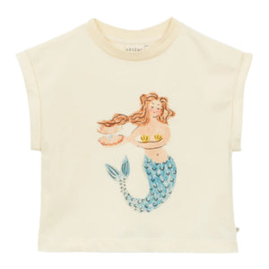 The Girls' Feliciane T-Shirt by Arsene & Les Pipelettes is a cream-colored organic cotton tee with short sleeves, showcasing a mermaid illustration holding a shell and cup, with long hair and a blue-scaled tail.