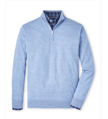 The Peter Millar Autumn Crest Quarter-Zip in light blue, crafted from a soft Merino wool blend, is layered over a blue plaid button-down and displayed flat against a white background.