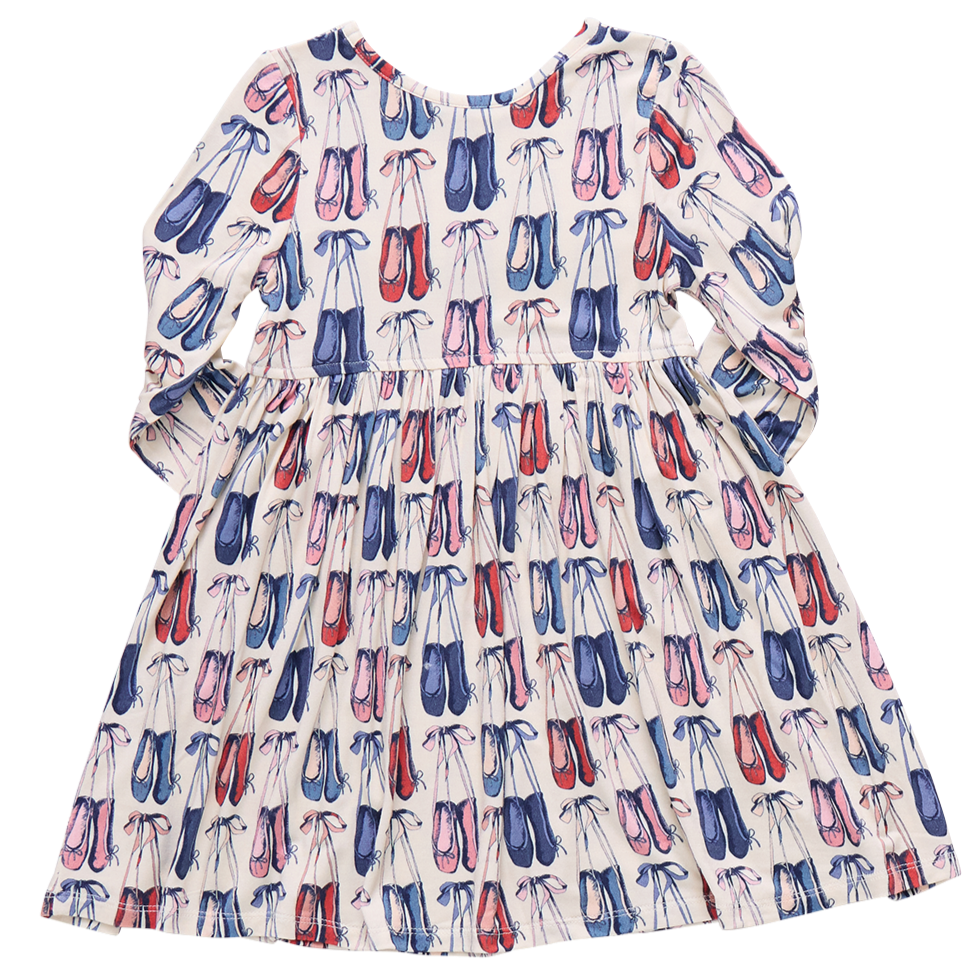 The Pink Chicken Girls' Bamboo Steph Dress is a long-sleeved dress made from soft bamboo, featuring a pink and blue ballet shoe pattern on a white background.