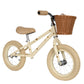 The Konges Slojd Balance Bike by Konges Slojd is a beige children's balance bicycle featuring a sturdy steel frame, a brown wicker basket on the handlebars, and small illustrations of bees on its lightweight design.