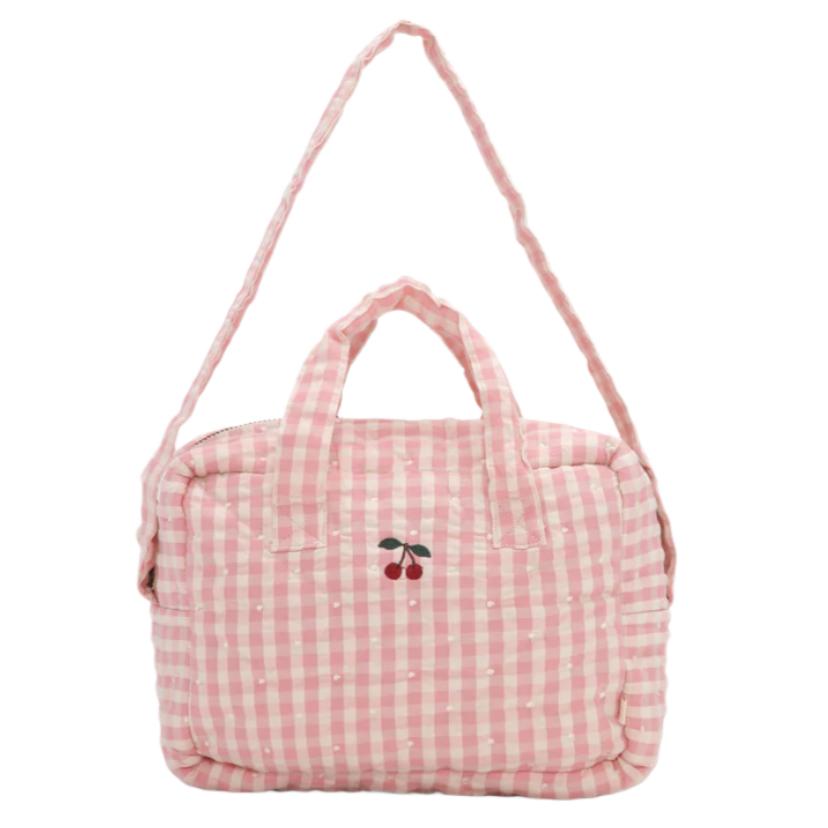 The Konges Slojd Doll Bag by Konges Slojd is a pink and white checkered changing bag with two handles and a shoulder strap. Made of 100% cotton, it features a small embroidered cherry design on the front.