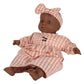 A brown-skinned baby doll dressed in the Konges Slojd Doll Clothes Set, a pink and white checkered outfit made from organic cotton with a matching headband. This ensemble by Konges Slojd is certified by OEKO-TEX® STANDARD 100 and features cherry embroidery on the chest.