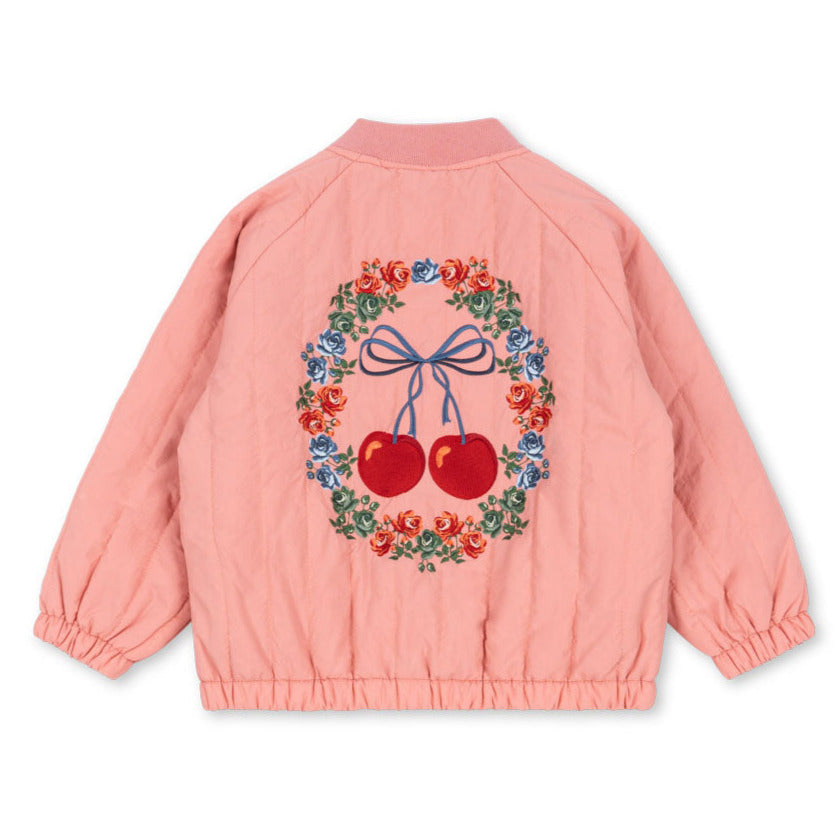 The Konges Slojd Juno Bomber Jacket is a pink thermo jacket featuring a floral wreath and two cherries design on the back, offering water-repellent protection.