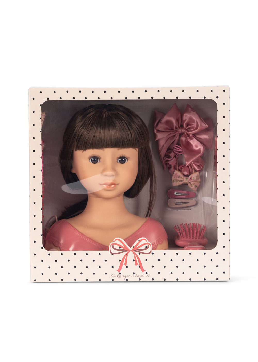 The Konges Slojd Stella Styling Doll with brunette hair comes in a charming polka dot box, ideal for creative hair styling. It includes pink hair accessories: a bow, clips, and a comb to spark imagination.