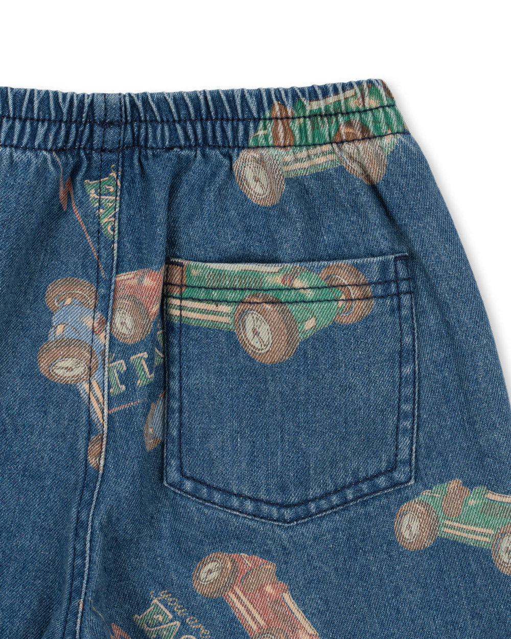 Close-up of Konges Slojd Baby Boys' and Boys' Magot Pants in blue denim with a straight fit, elastic waist, back pocket, and a colorful vintage race car print.