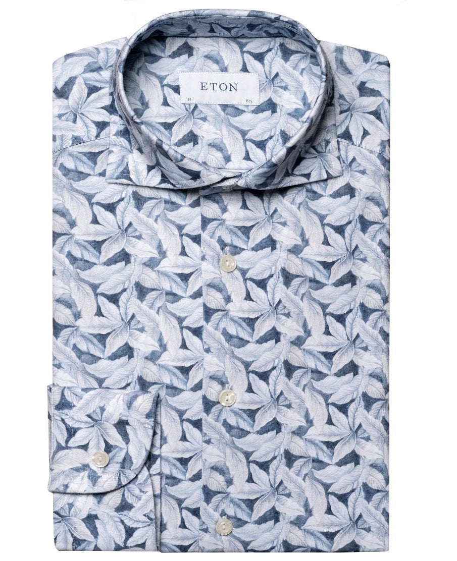 A folded Eton Four-Flex Shirt, Slim Fit, featuring a blue and white leaf pattern design with subtle palm print accents.