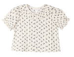 The Girls’ Liv Blouse by Rylee & Cru is a white short-sleeve button-down blouse featuring a scalloped, ruffled collar, small dark floral print, front button closure, and puffed sleeves.