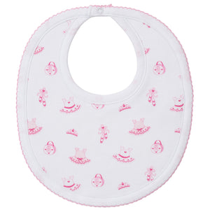The Kissy Kissy Ready to Dance Bib is made from soft Pima cotton with a pink trim, decorated with prints of dresses, purses, and flowers. It features a button closure at the neck—perfect for keeping mealtime messes away.