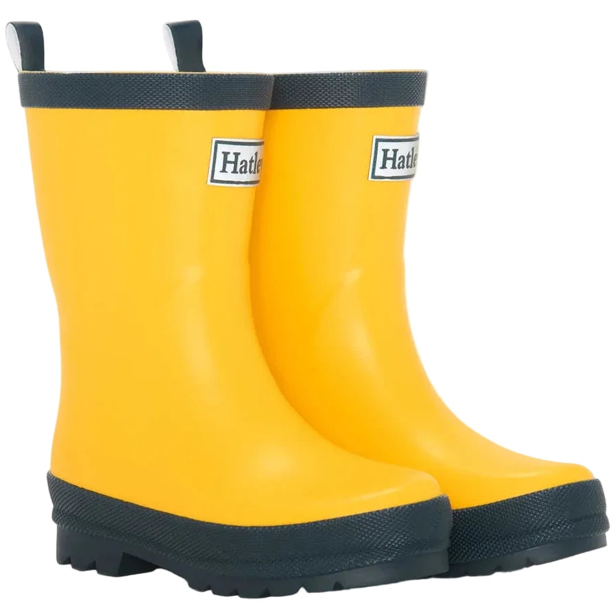 A pair of Hatley Yellow & Navy Matte Rain Boots for kids, featuring slip-resistant rubber soles and navy trim, are placed side by side on a white background.