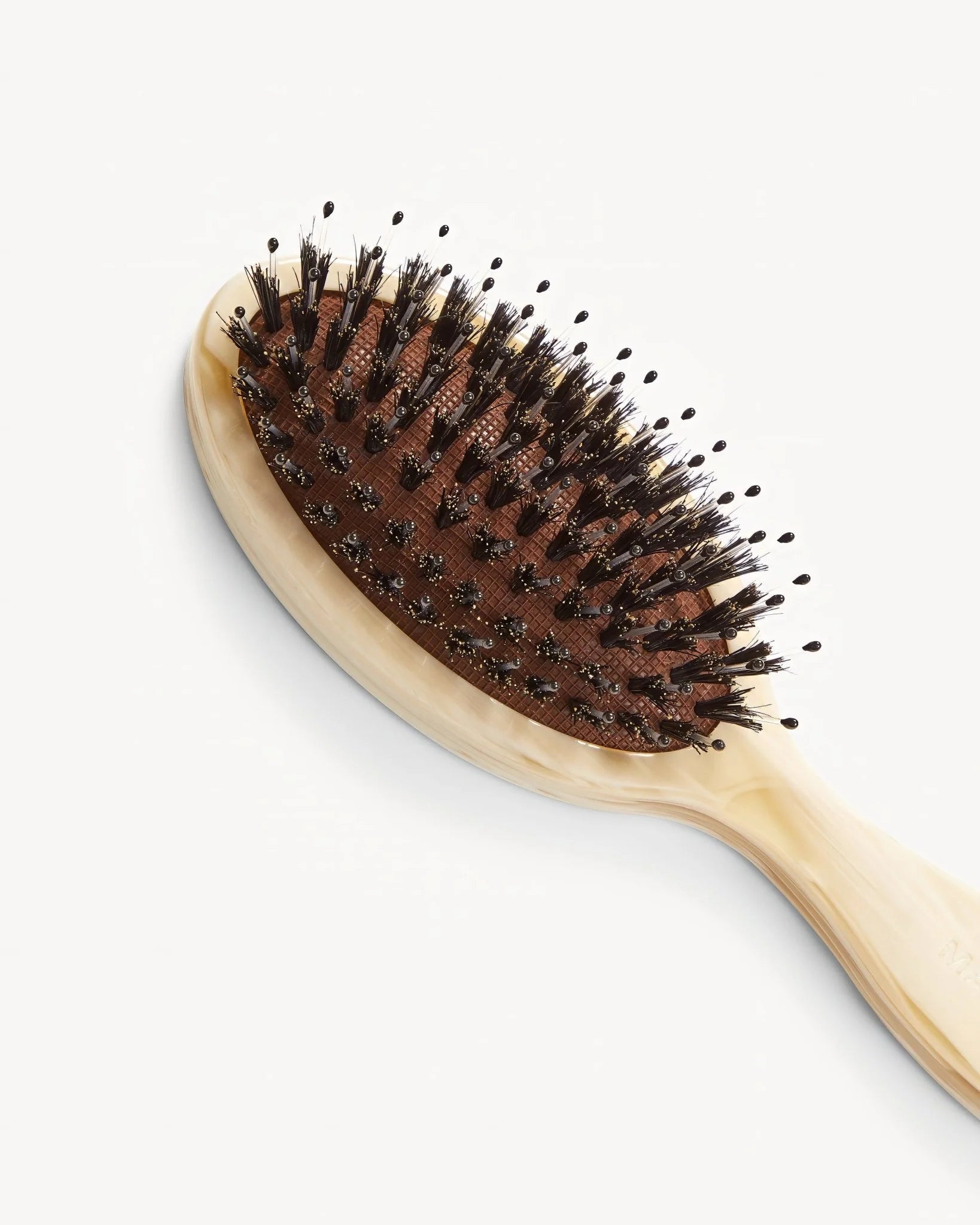 A close-up of the Machete Petite Travel Hair Brush, featuring dark detangling bristles and a light-colored bio-acetate handle, set against a plain white background.