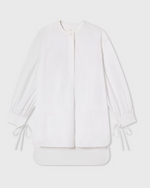 The CO Cuff Tie Shirt features long sleeves, a round neckline, henley placket, gathered cuffs, and ribbon ties at the wrists, shown laid flat on a light background.