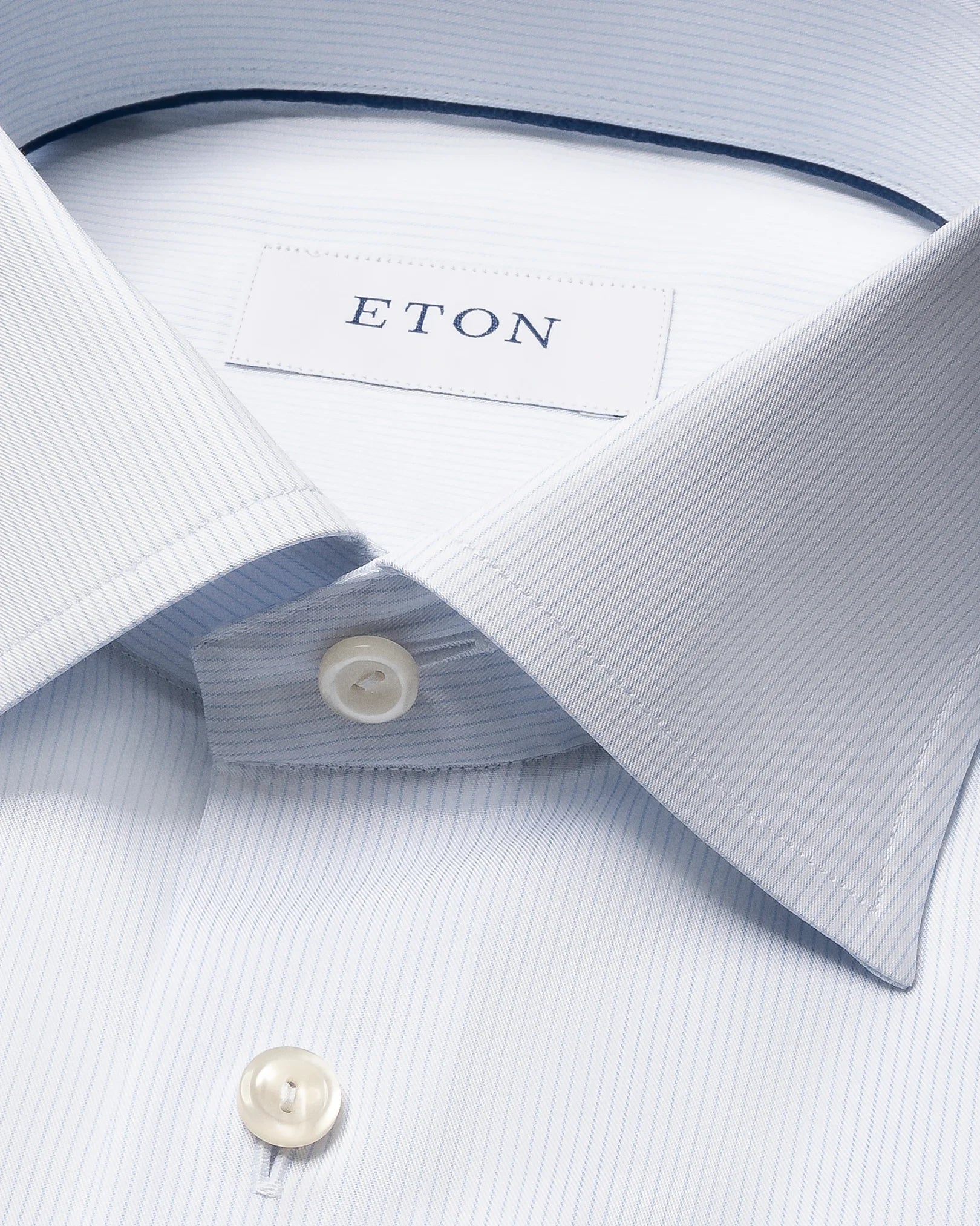 Close-up of the Eton Contemporary Striped Twill Shirt in light blue, featuring subtle stripes, a pointed collar, white buttons, and the signature Eton label inside the collar. Made from 100% cotton, this shirt combines comfort and refined elegance for any occasion.