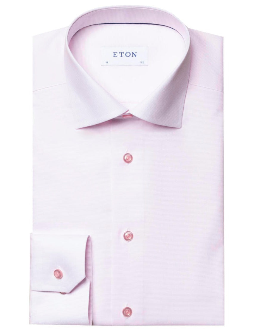 A neatly folded, light pink Eton Twill Shirt with long sleeves, matching pink buttons, an Eton label, and a versatile collar in a slim fit.