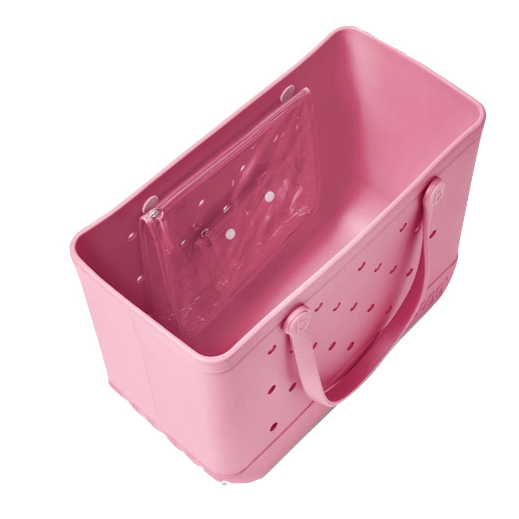 The Original Bogg® Bag by Bogg Bags is a spacious pink rectangular tote crafted from durable plastic, featuring sturdy handles and ventilation holes for breathability—ideal as a washable beach bag. Inside, it includes a clear zippered pouch for organizing your essentials.