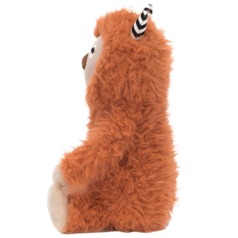 Side view of a fluffy, orange Jellycat Pip Monster with black and white striped horns and gingery fur sitting upright, showcasing its adorable suedey truffle nose.